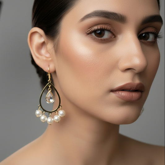 Gold earrings with pearl-like beads on a dark background