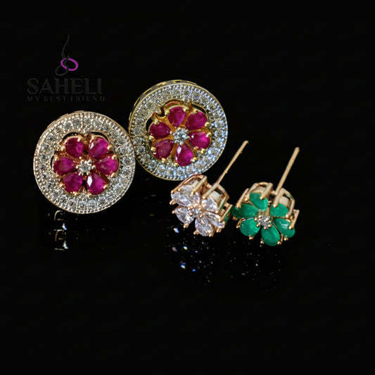 Pair of diamond and gemstone earrings on a gray background with 'Saheli' branding.