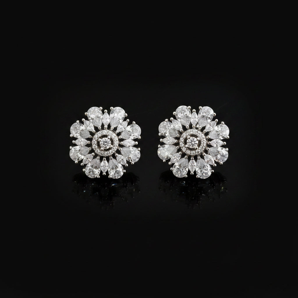 Pair of diamond earrings on a dark background with 'Saheli' branding.