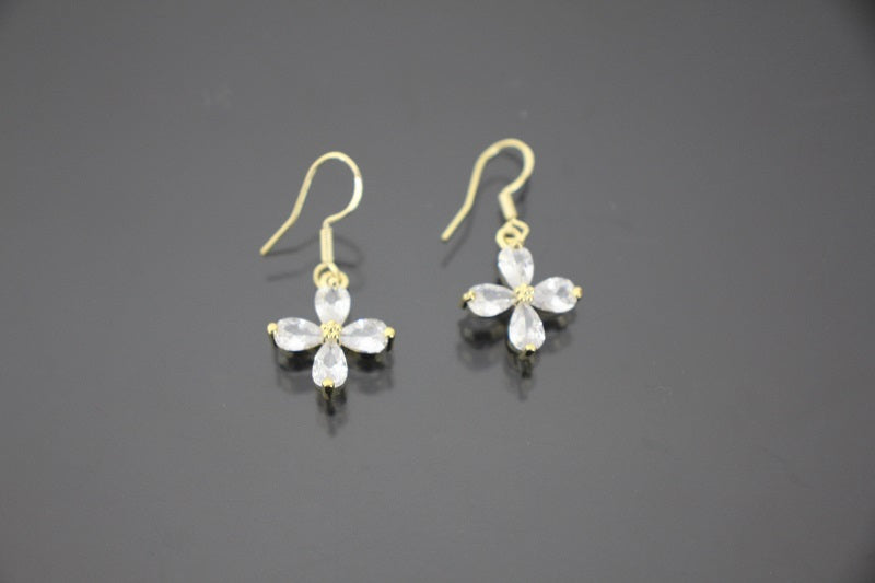 Gold earrings with clear gemstones on a dark gray background