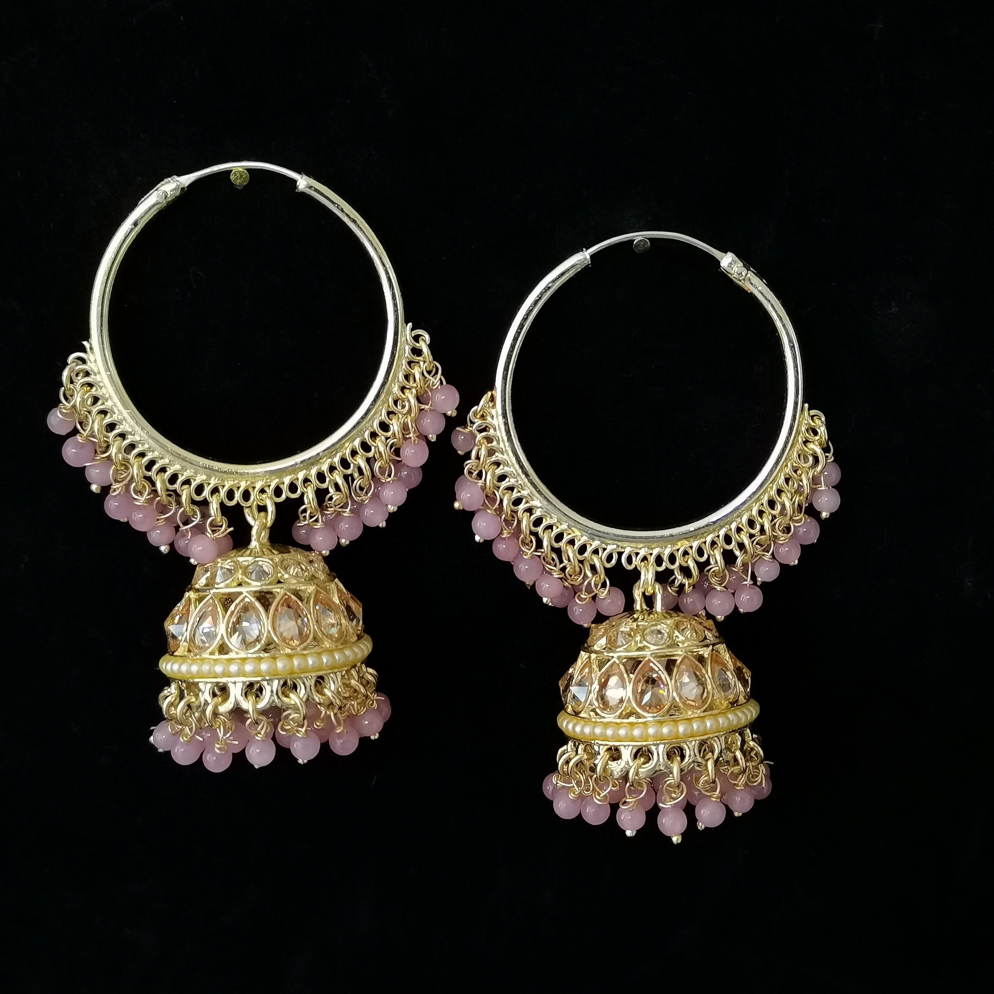 Pair of gold hoop earrings with pink gemstones on a black background