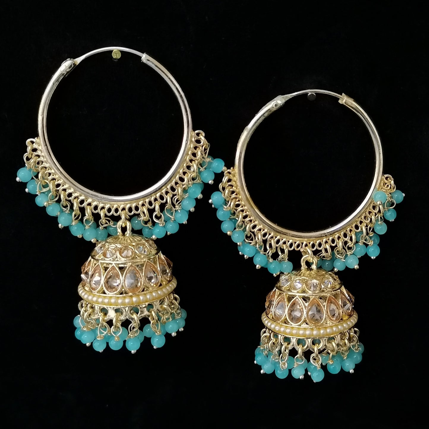 Pair of gold and turquoise hoop earrings on a black background