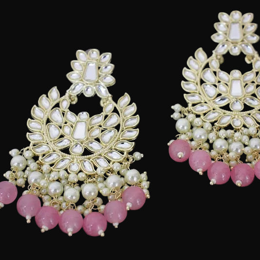 Pair of gold and pink earrings with 'Saheli' branding on a dark background