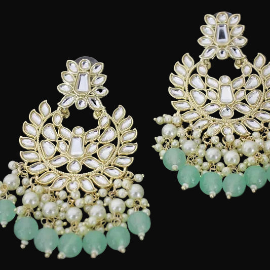 Pair of gold and green earrings with 'Saheli' branding on a dark background