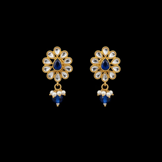 Gold and blue gemstone earrings on a gray stand with 'SAHELI' branding.