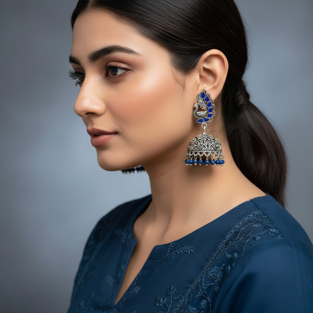 Silver and blue earrings on a gray stand with 'SAHELI' branding.