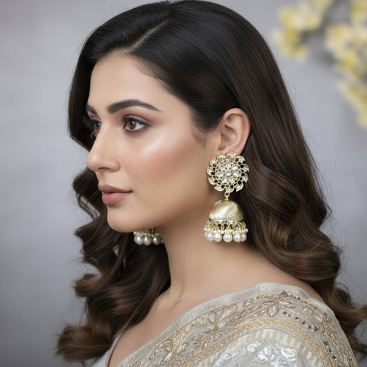 Gold and pearl earrings on a black stand against a gray background