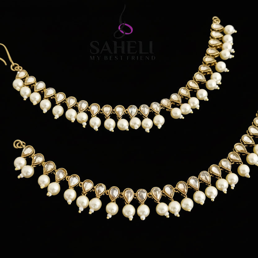 Pearl necklace with gold accents on a dark background, featuring the brand 'Saheli'.