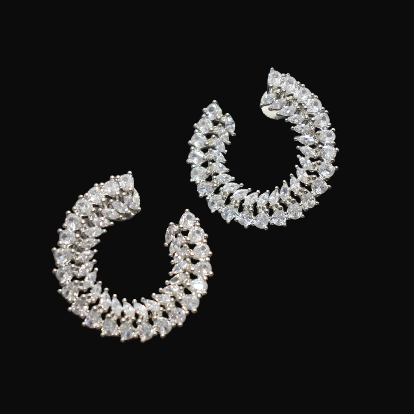 Pair of silver hoop earrings with clear stones on a gray background