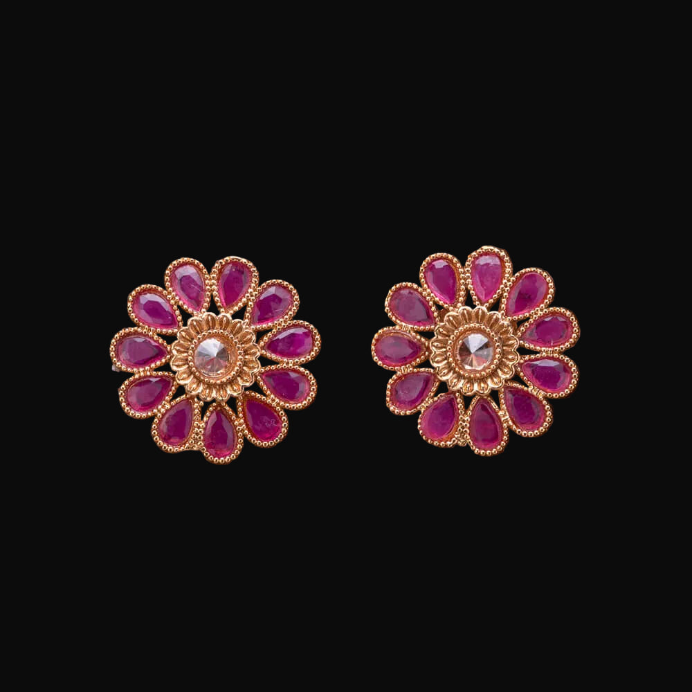 Pair of gold and pink floral earrings on a wooden surface