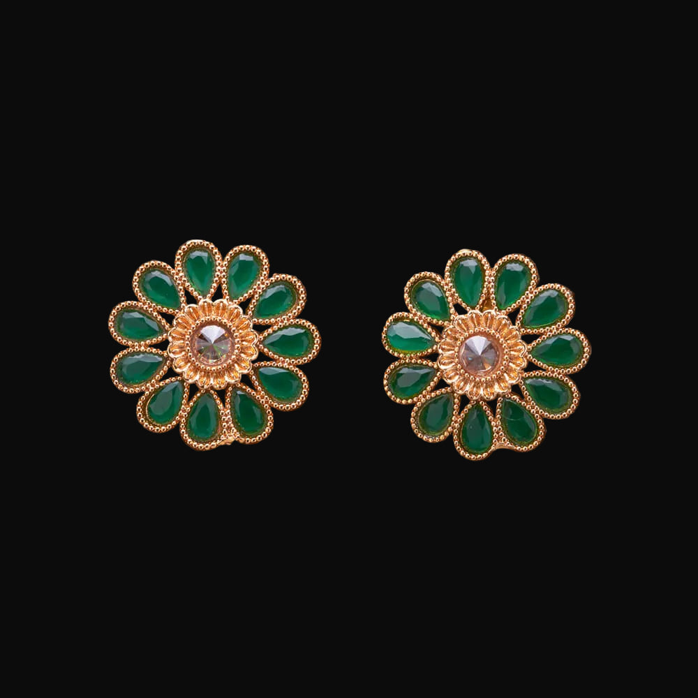 Gold and green floral earrings on a wooden surface