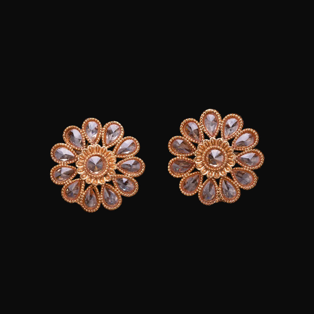 Pair of gold floral earrings with clear stones on a wooden surface