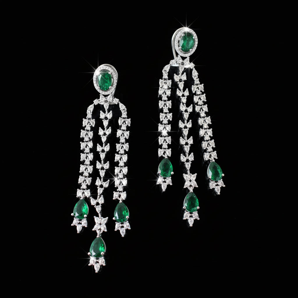 Pair of earrings with green gemstones and silver chains on a gray background