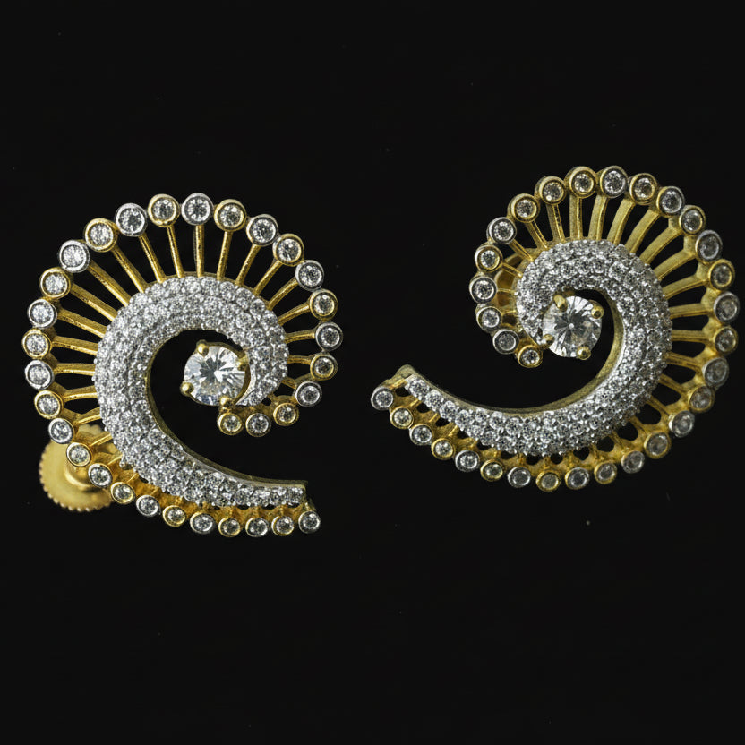 Pair of spiral-shaped earrings with gold and silver details on a dark background, featuring the brand 'Saheli'.