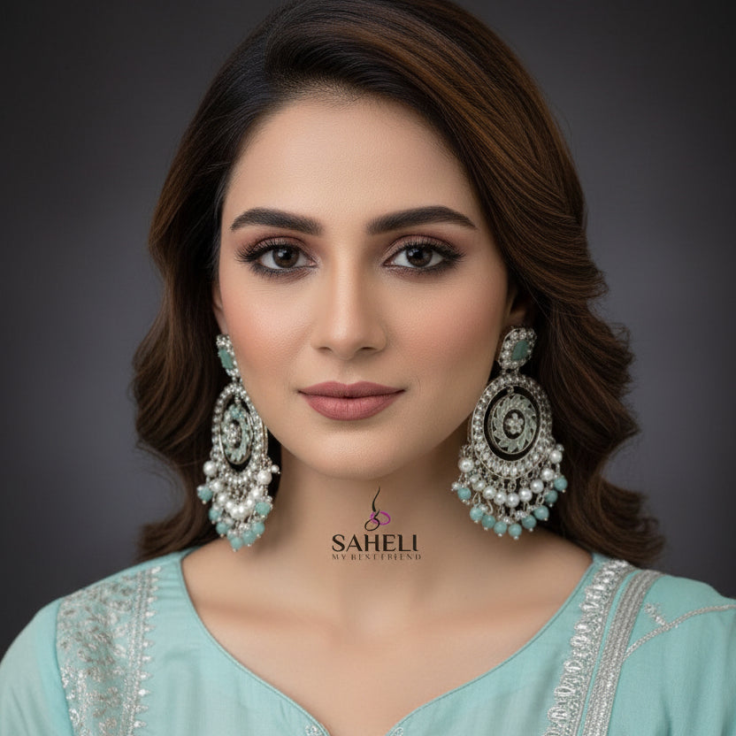Pair of silver and turquoise earrings with 'SAHELI' branding on a dark background