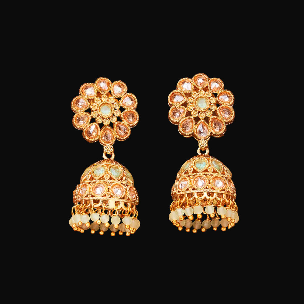 Gold earrings with floral and bell design on a brown background