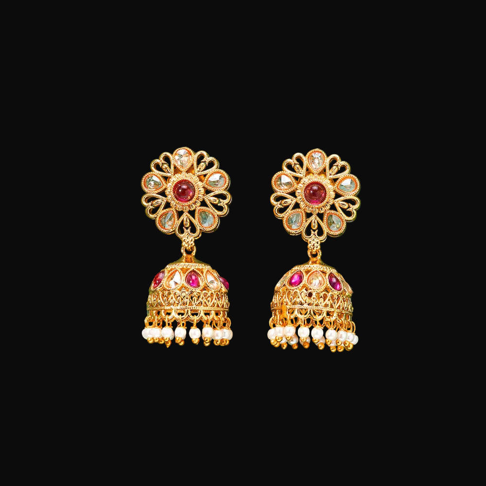 Gold earrings with red and clear gemstones on a green background