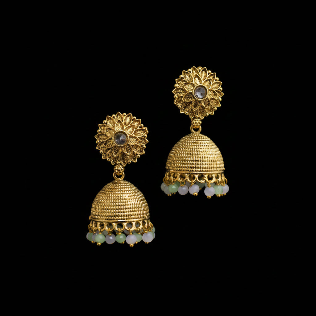 Gold jhumka earrings on a gray stand with a neutral background