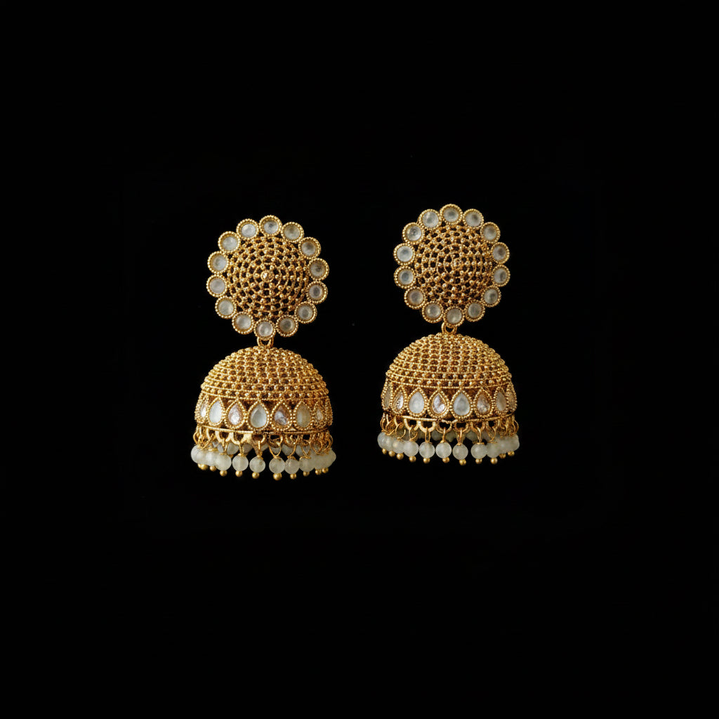 Gold and pearl earrings on a gray stand with a dark background