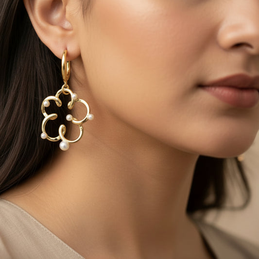 Gold earrings with pearl-like beads on a dark background
