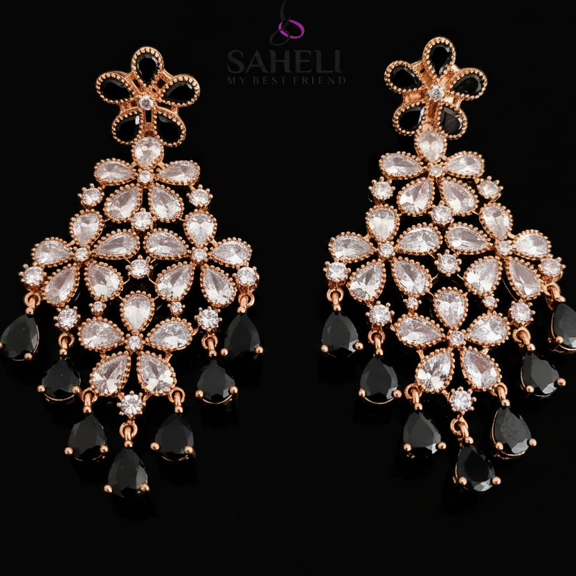 Ornate earrings with clear stones and gold accents on a dark background, branded 'Saheli'.