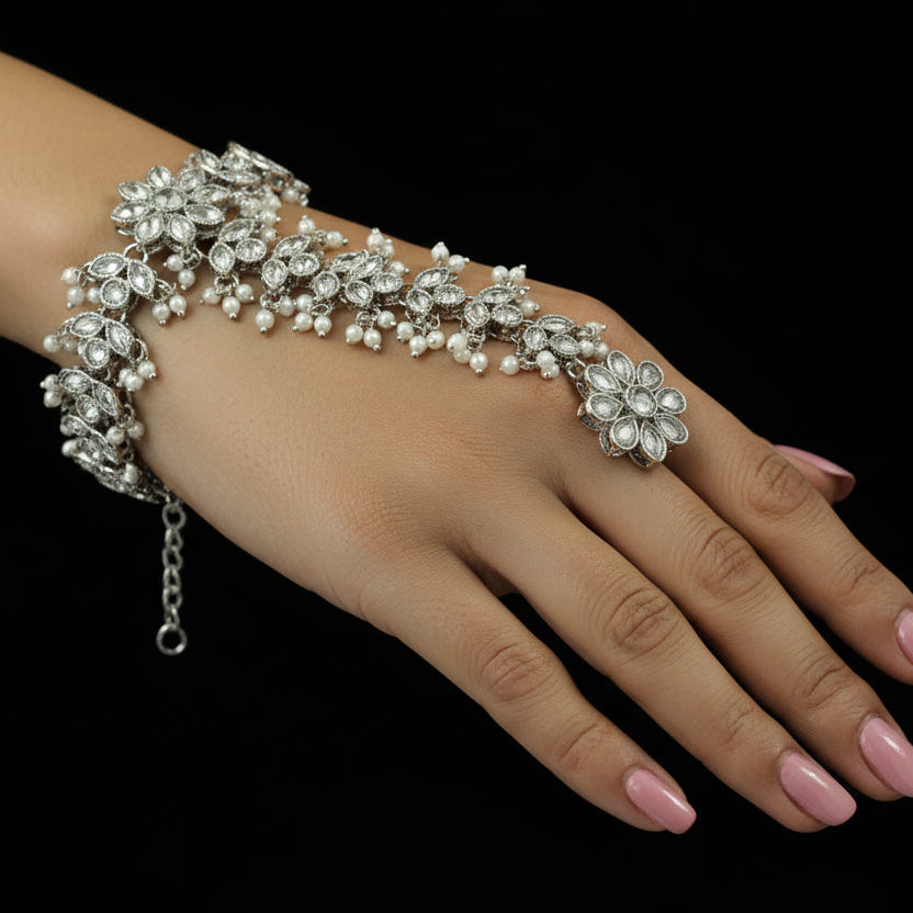 Silver bracelet with floral designs on a black mannequin hand, branded 'Saheli'.