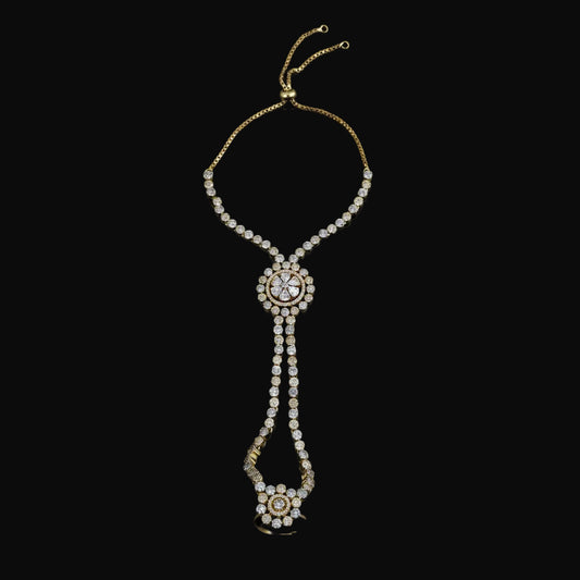 Gold-toned chain necklace with multiple rows of clear rhinestones, featuring a central oval cluster and a dangling floral pendant, displayed on a solid pink background.