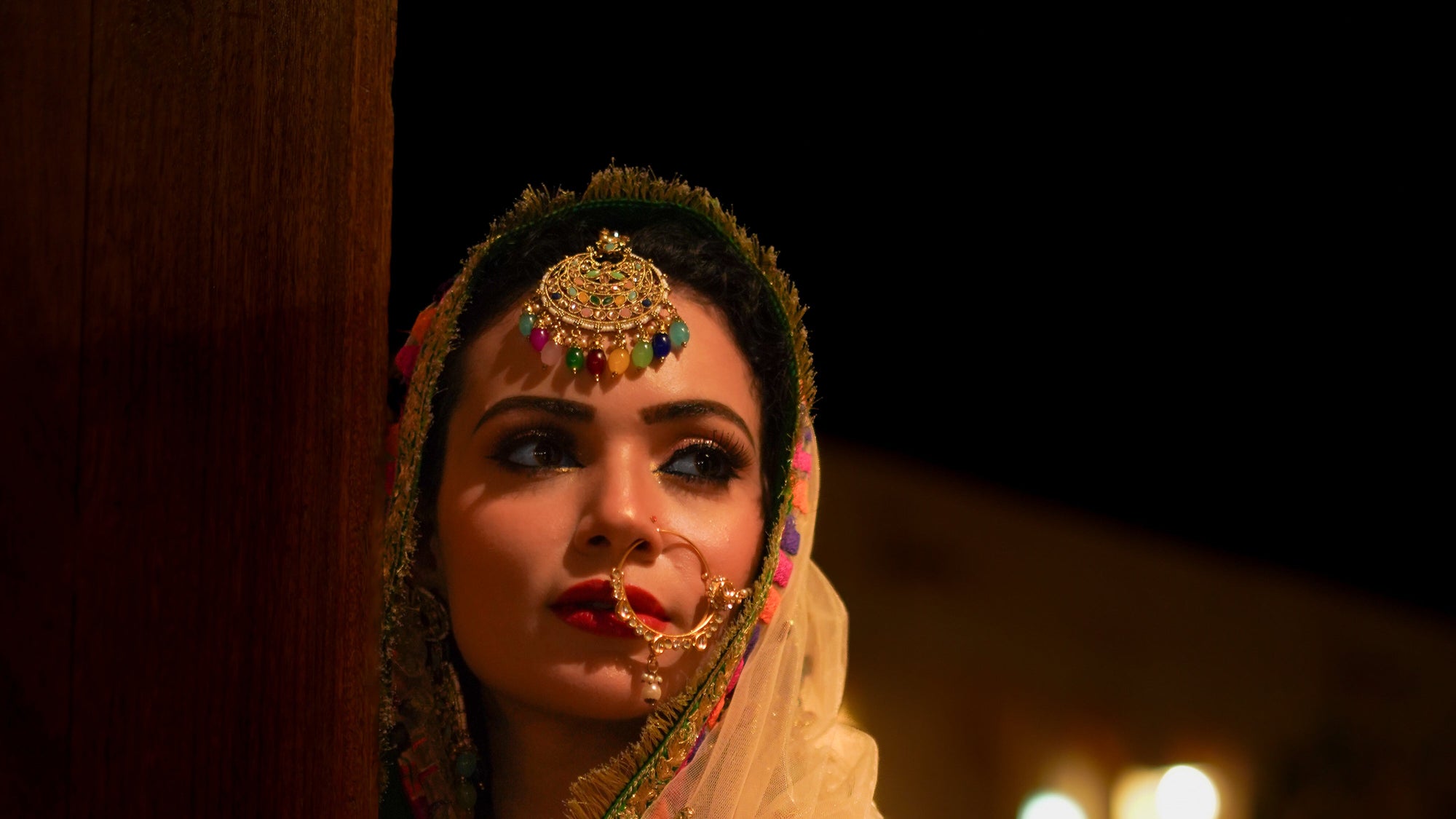 Woman in traditional attire with jewelry and a dark background