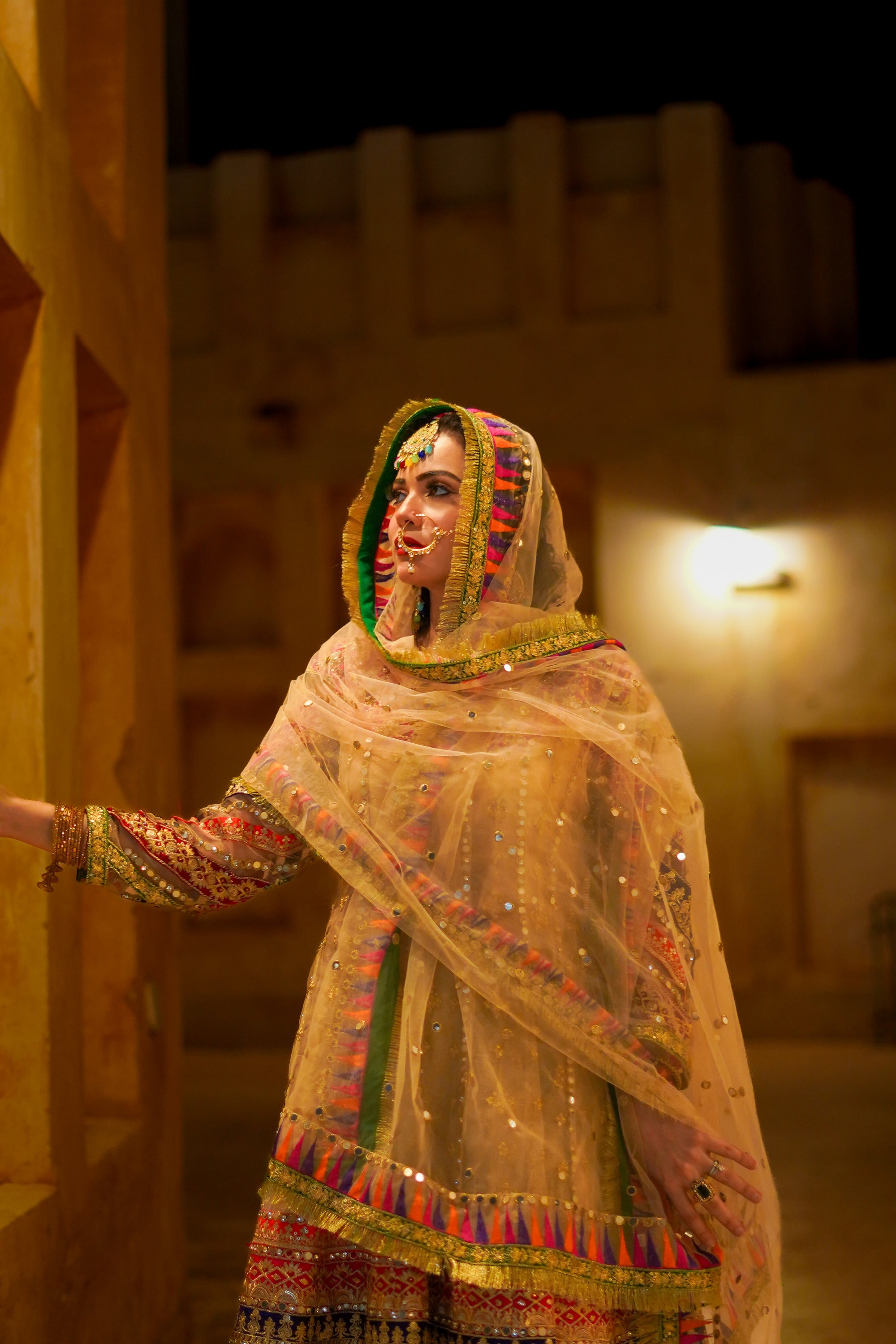 Woman in traditional attire with a colorful headscarf in an indoor setting.