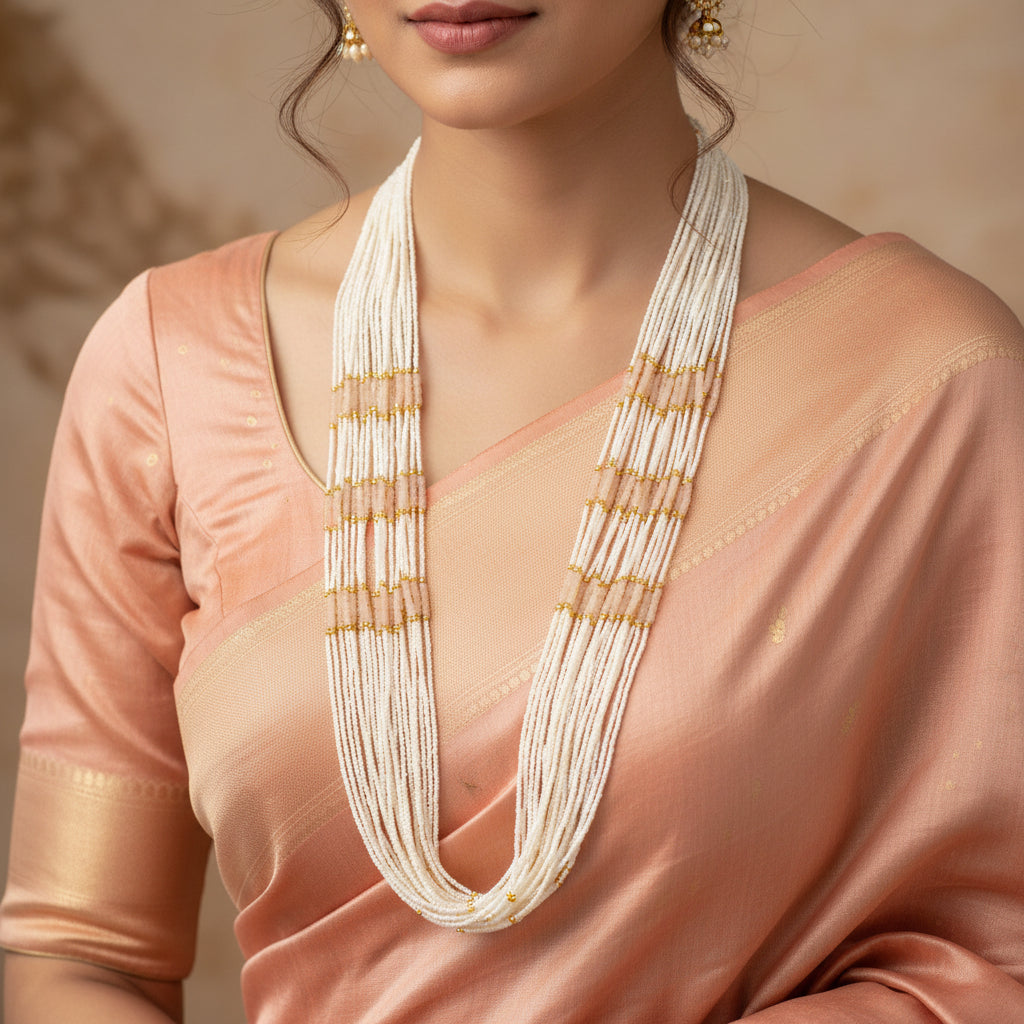Long necklace with white and gold beads on a dark background