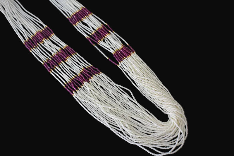 White beaded belt with purple and gold accents on a dark background