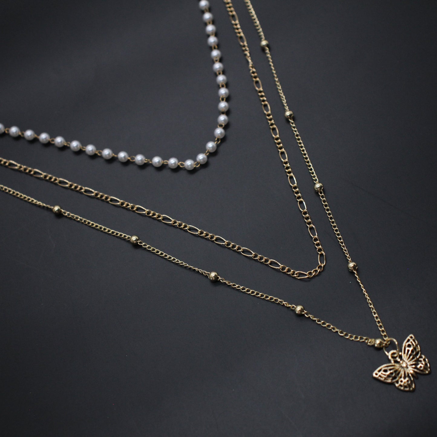 Three necklaces with different designs on a dark background
