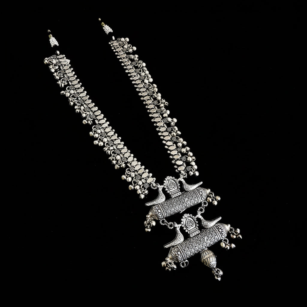 Silver necklace with intricate designs on a reflective surface