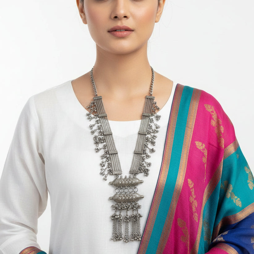 Silver necklace with intricate designs on a reflective surface