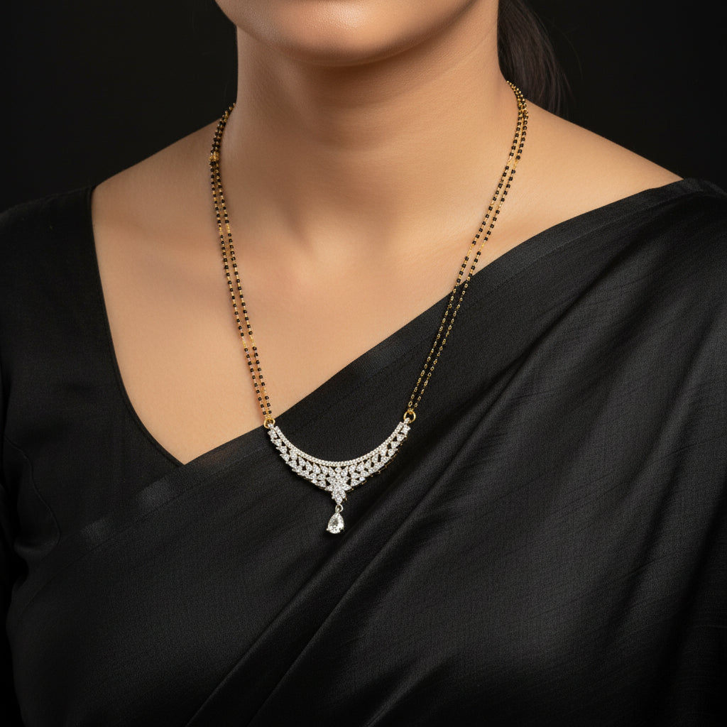 A gold chain necklace featuring a silver-toned crescent-shaped pendant embellished with clear stones and a teardrop crystal drop, displayed on a black textured background.