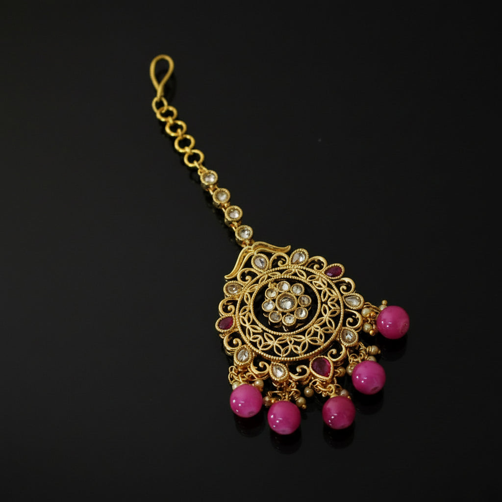 Gold necklace with pink beads on a dark background, featuring the brand 'SAHELI'.