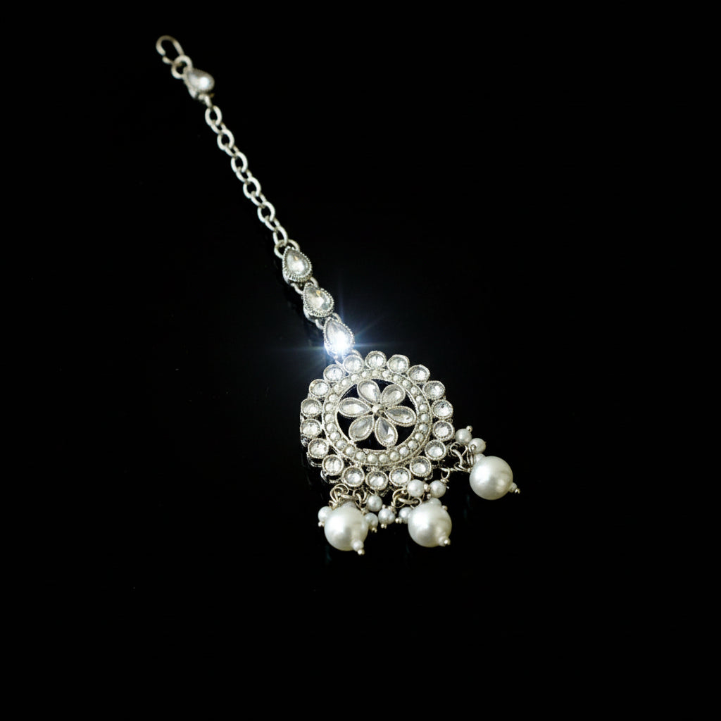 Silver necklace with floral design and pearl beads on a dark background