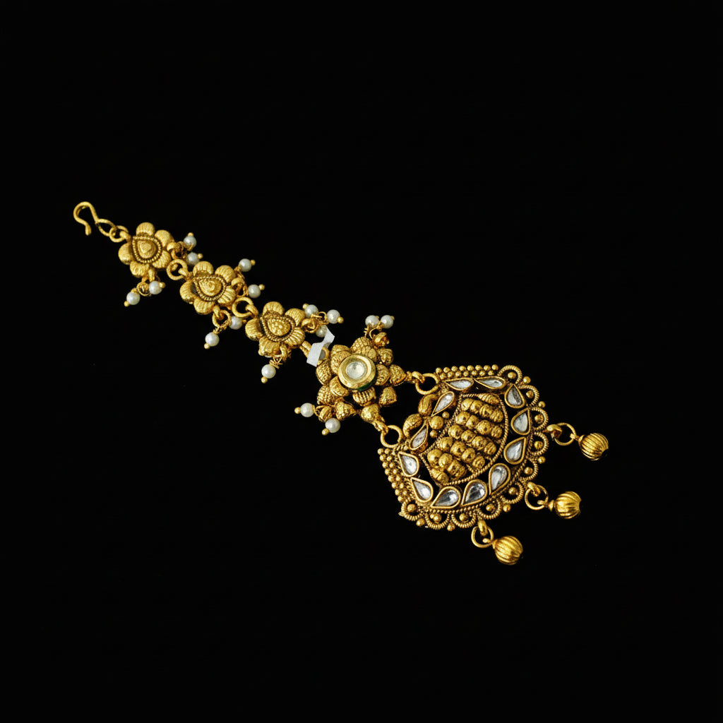 Gold necklace with intricate designs on a dark background, featuring the brand 'Saheli'.