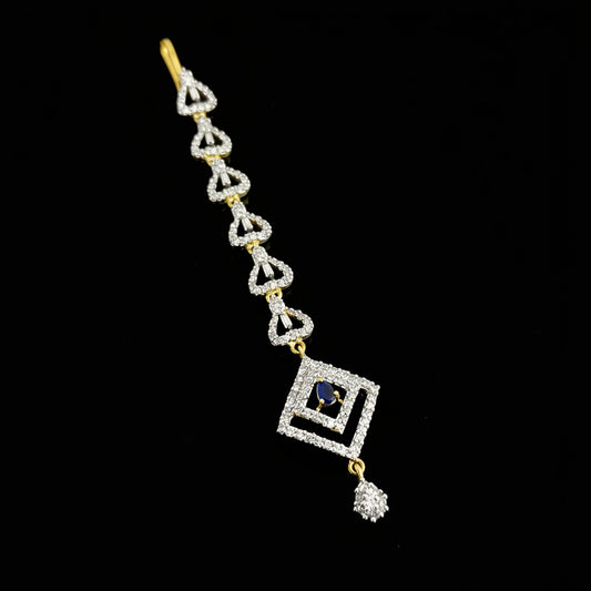Delicate silver and gold bracelet with a blue gemstone on a gray background, featuring the brand 'Saheli'.