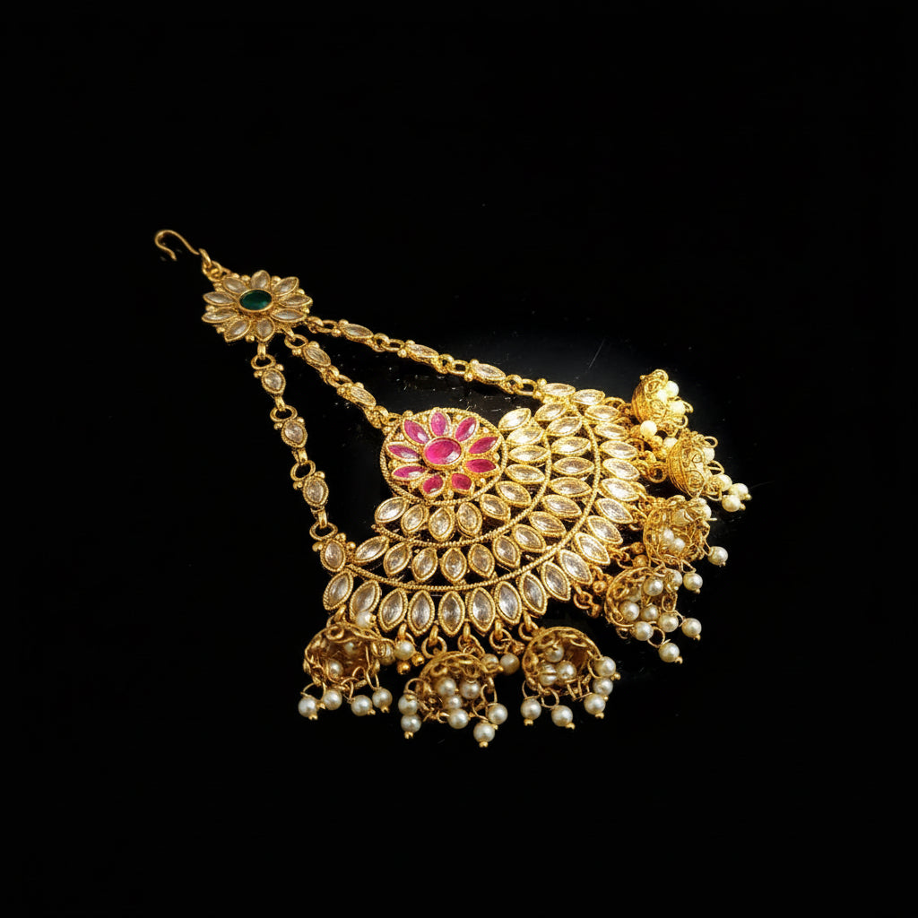 Gold jewelry with red gemstone on a dark background, featuring the brand 'Saheli'.