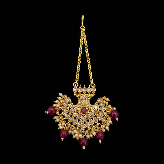 Gold necklace with red gemstones on a gray background, featuring the brand 'Saheli'.