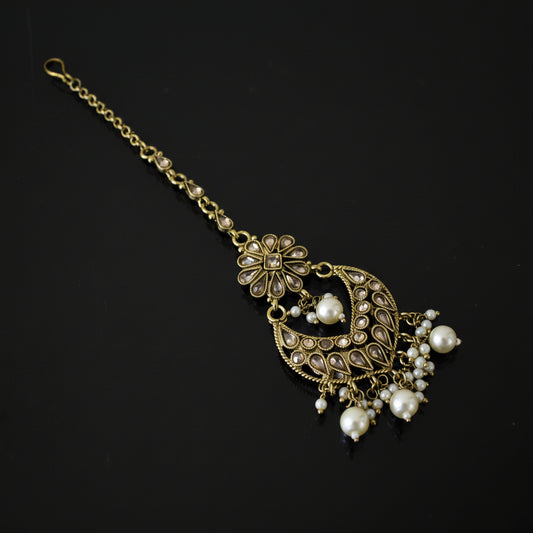 Decorative hair accessory with gold chain and pearl-like beads on a dark background