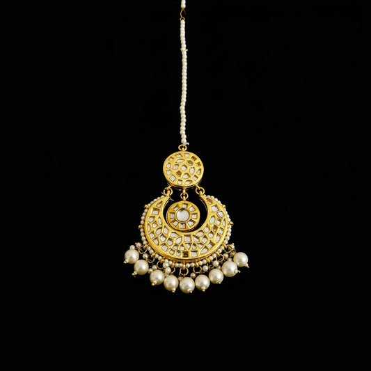 Gold necklace with pearls on a dark background, featuring the brand 'Saheli'.