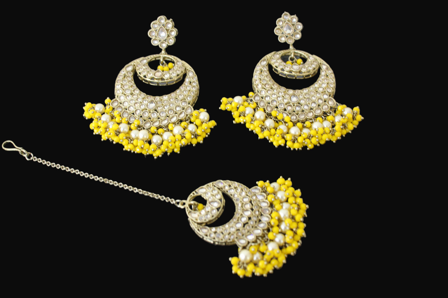 Ornate earrings with yellow and white stones on a dark background