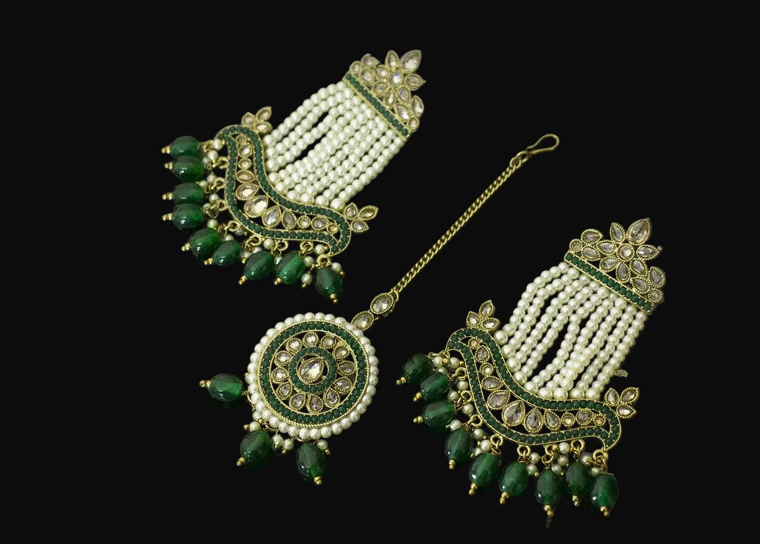 Ornate earrings with green and gold details on a dark background