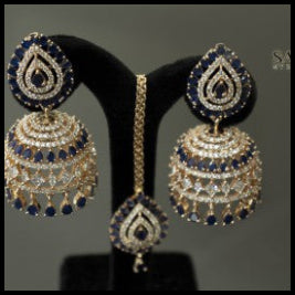 Jewelry set with earrings on a black stand against a gray background, featuring the brand 'Saheli'.