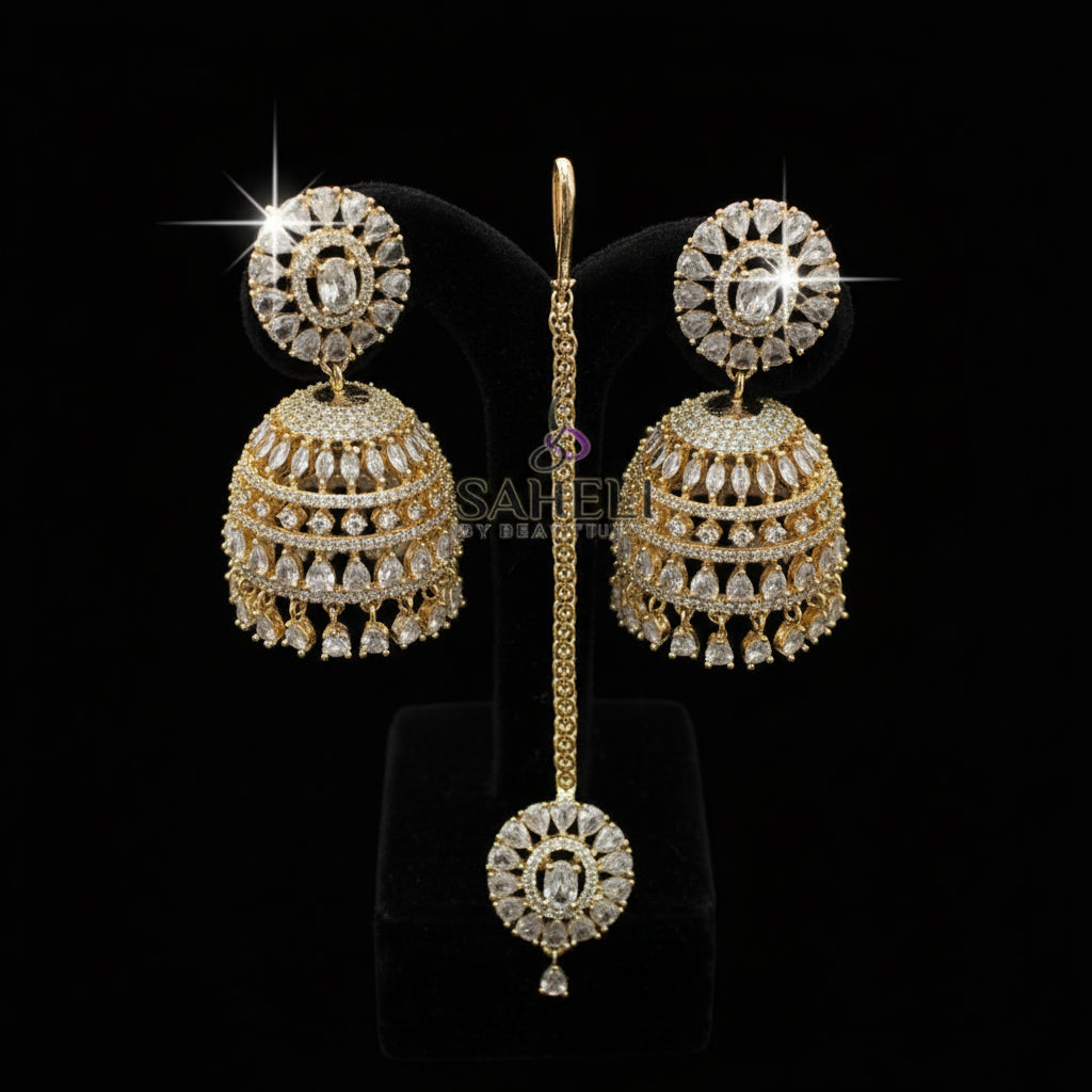 Gold earrings on a black stand with 'Saheli' branding.