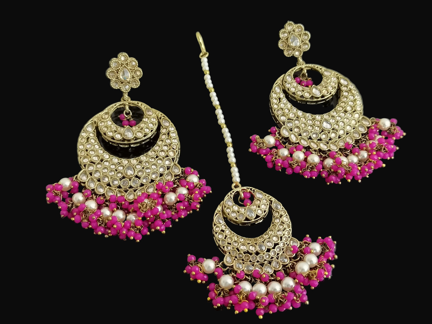 Ornate earrings with pink and white stones on a dark background