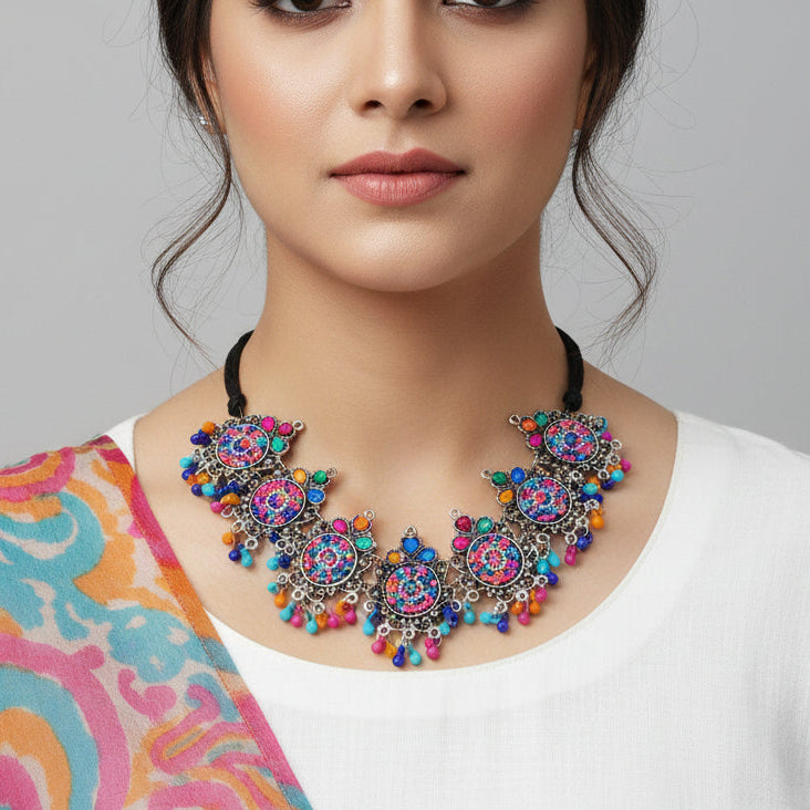 Colorful necklace with multicolored beads on a dark background, featuring the brand 'Saheli'.