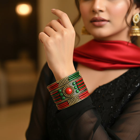 Decorative bracelet with green, red, and gold colors on a gray cushion against a dark background